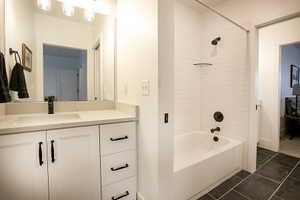 Bathroom featuring a white vanity with integrated sink, a large mirror, and overhead lighting