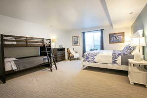 Carpeted room featuring white walls, a single window with blinds and blue curtains, and a painted accent wall