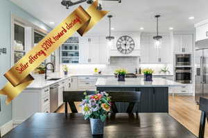Gourmet kitchen featuring white shaker cabinetry, an oversized island with contrasting base cabinetry, stainless steel appliances, pendant lighting, and wood-finish flooring
