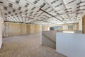 Spacious unfinished basement with exposed ceiling insulation, visible plumbing, and electrical lines