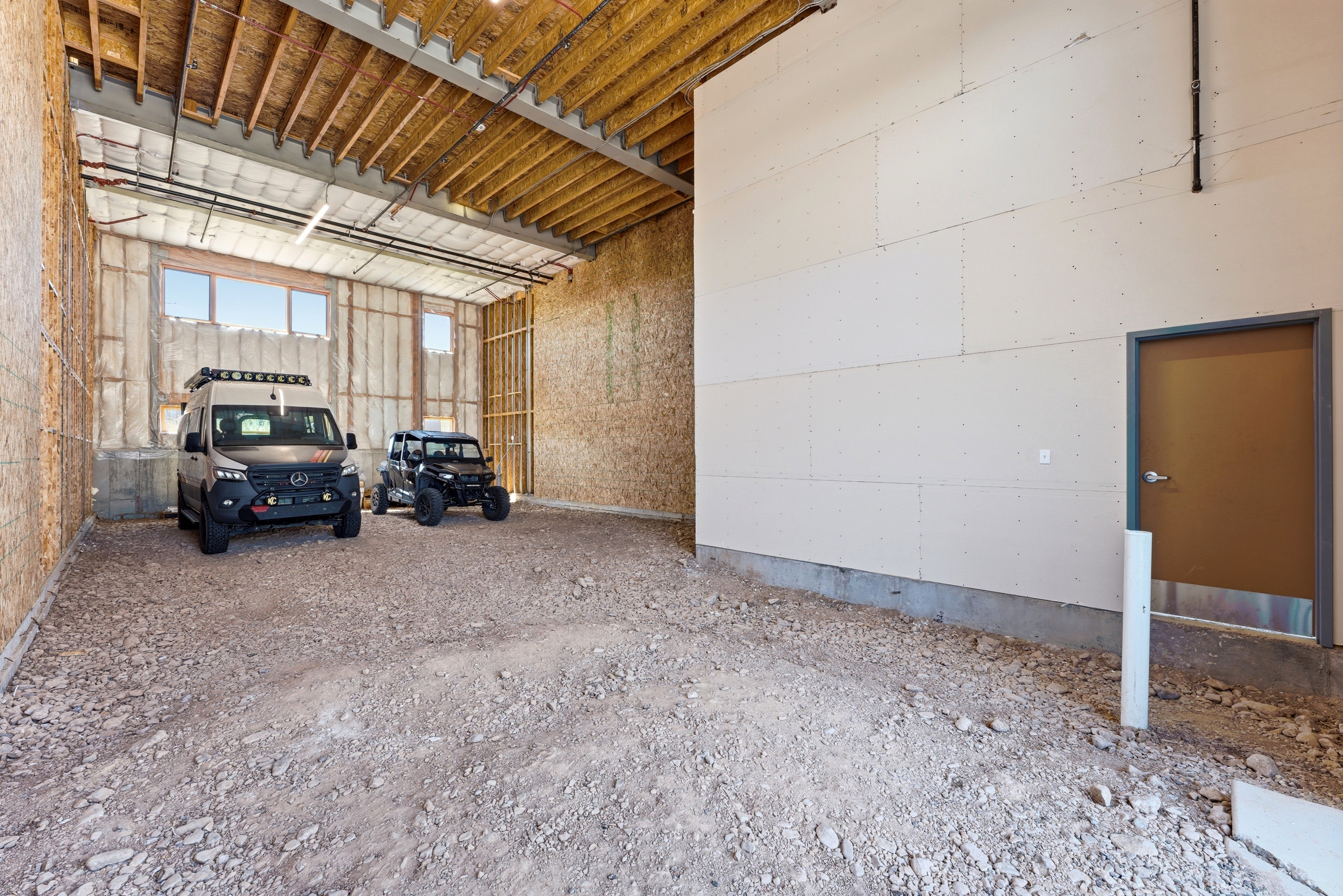 Spacious interior featuring exposed wood ceiling joists and unfinished wood paneling