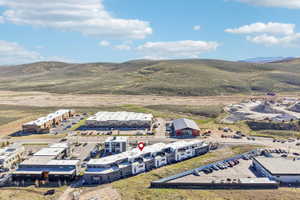 Modern multifamily residential buildings with distinct architectural designs, surrounded by expansive undeveloped hills