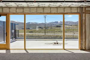 Expansive sliding glass doors open to a concrete deck, framed by rugged mountains under a clear sky
