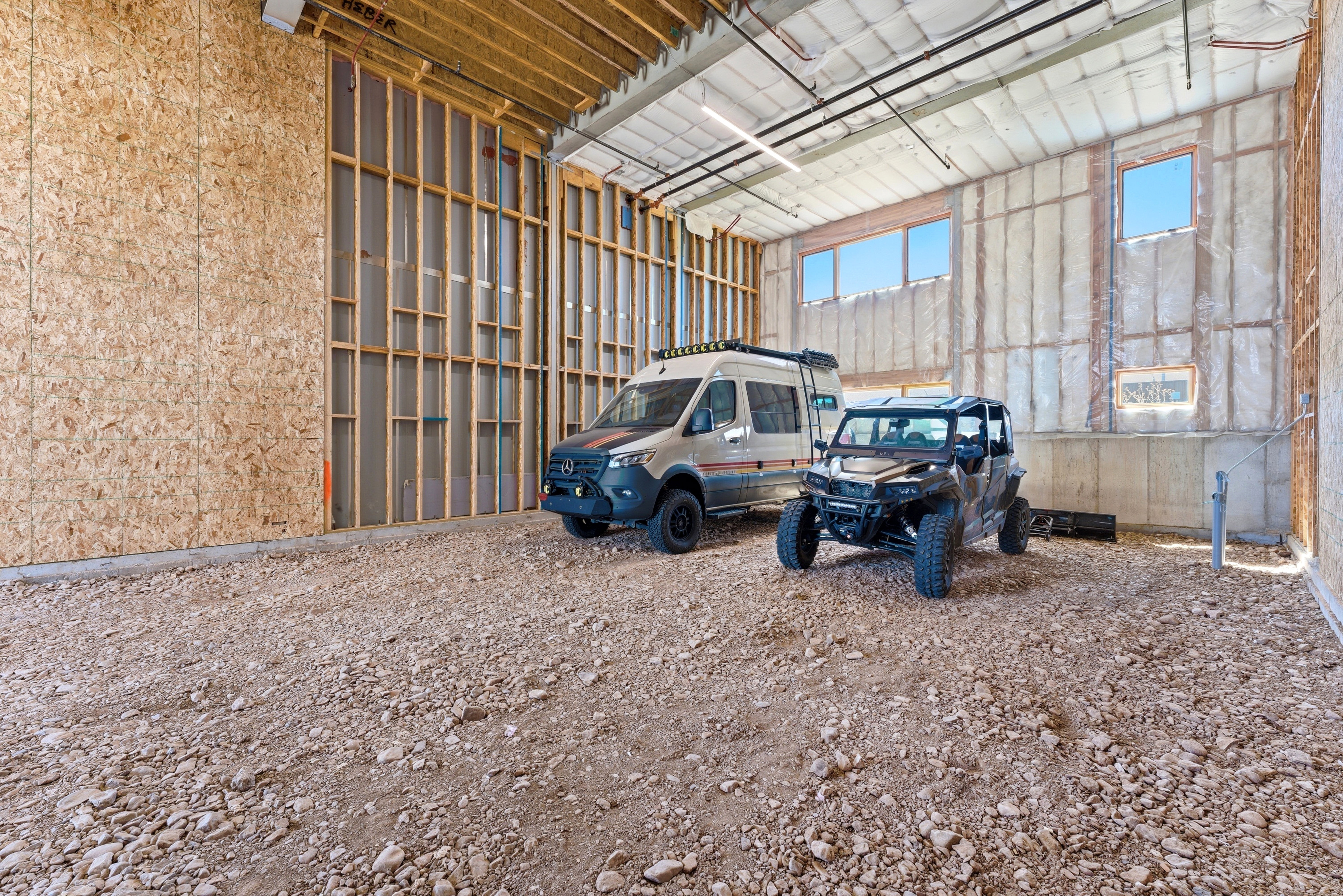 Spacious interior featuring exposed wood framing, insulated walls, concrete flooring, and multiple windows