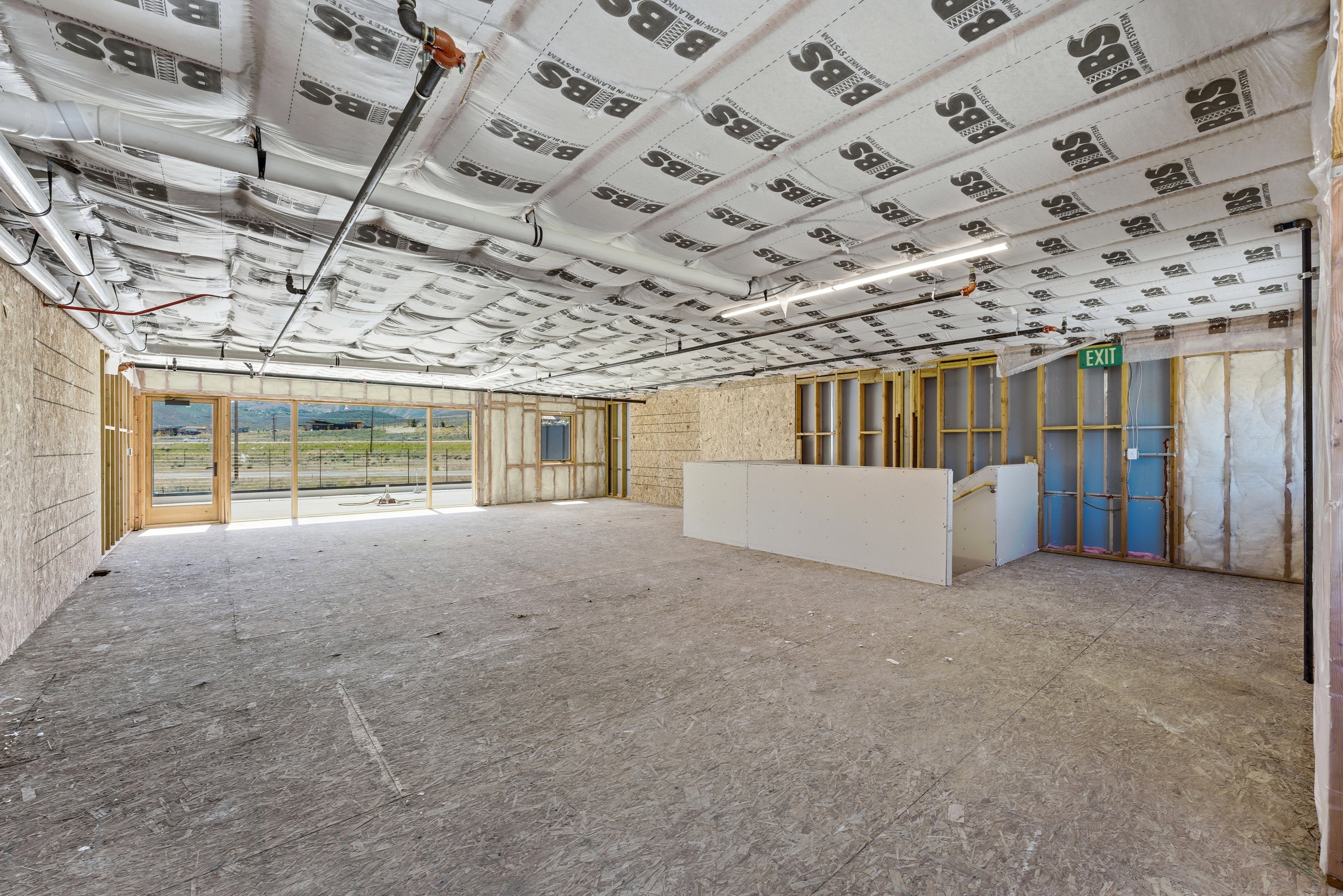 Expansive unfinished interior with concrete flooring and exposed ceiling insulation