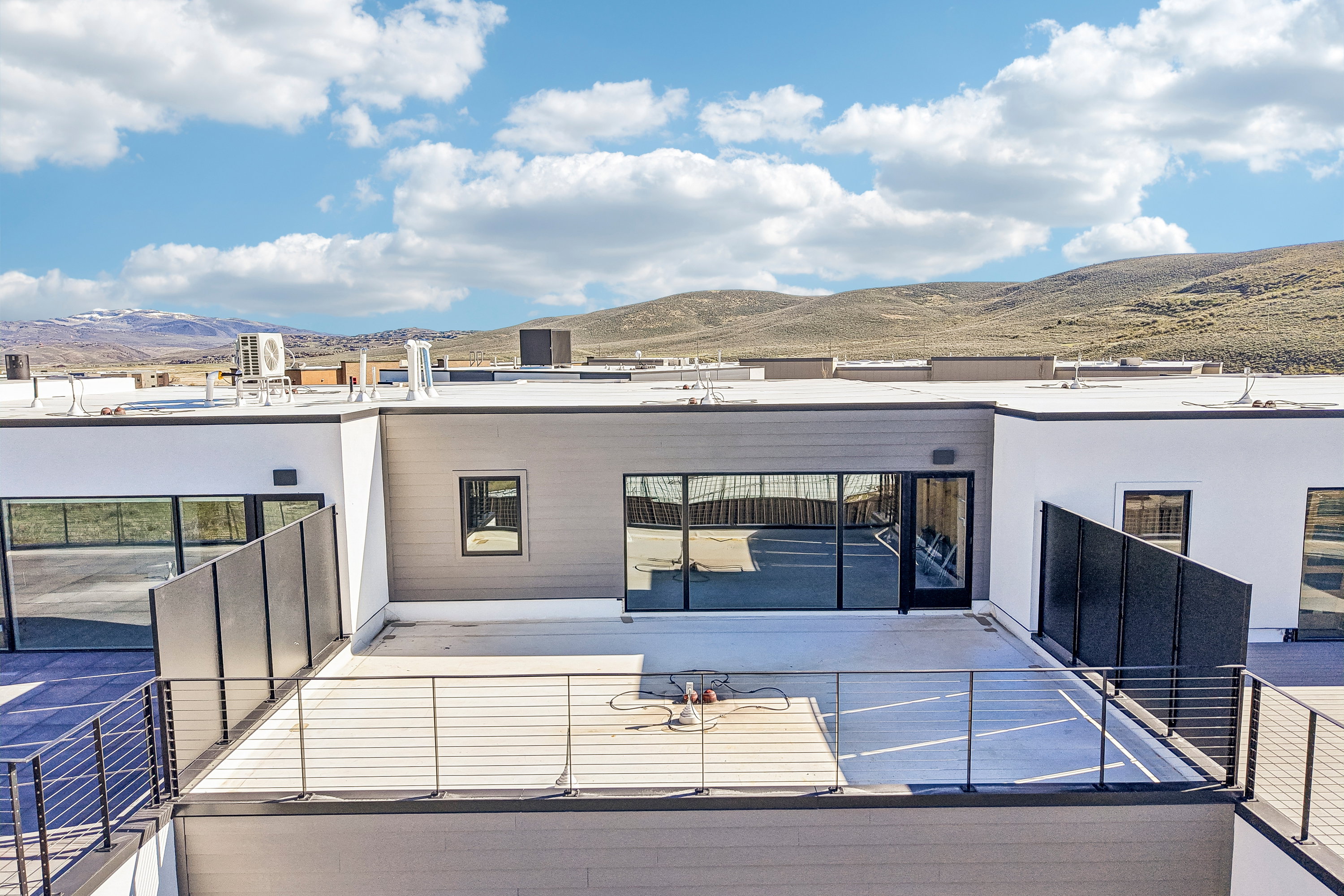 Rooftop patio featuring modern cable railings and direct access to an interior space via a glass panel door