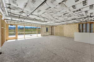 Open-concept interior space featuring exposed structural elements, a wood-framed glass door, and expansive windows