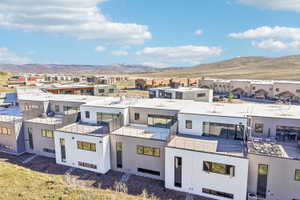 Modern multi-level townhome featuring a flat roofline, white and grey exterior paneling, and multiple private outdoor terrace spaces