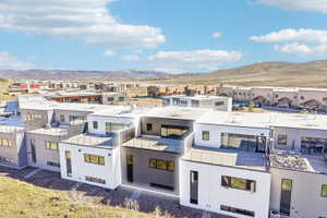 Modern multi-level exterior featuring white and charcoal-toned siding, expansive windows, flat roofs, and outdoor terrace spaces