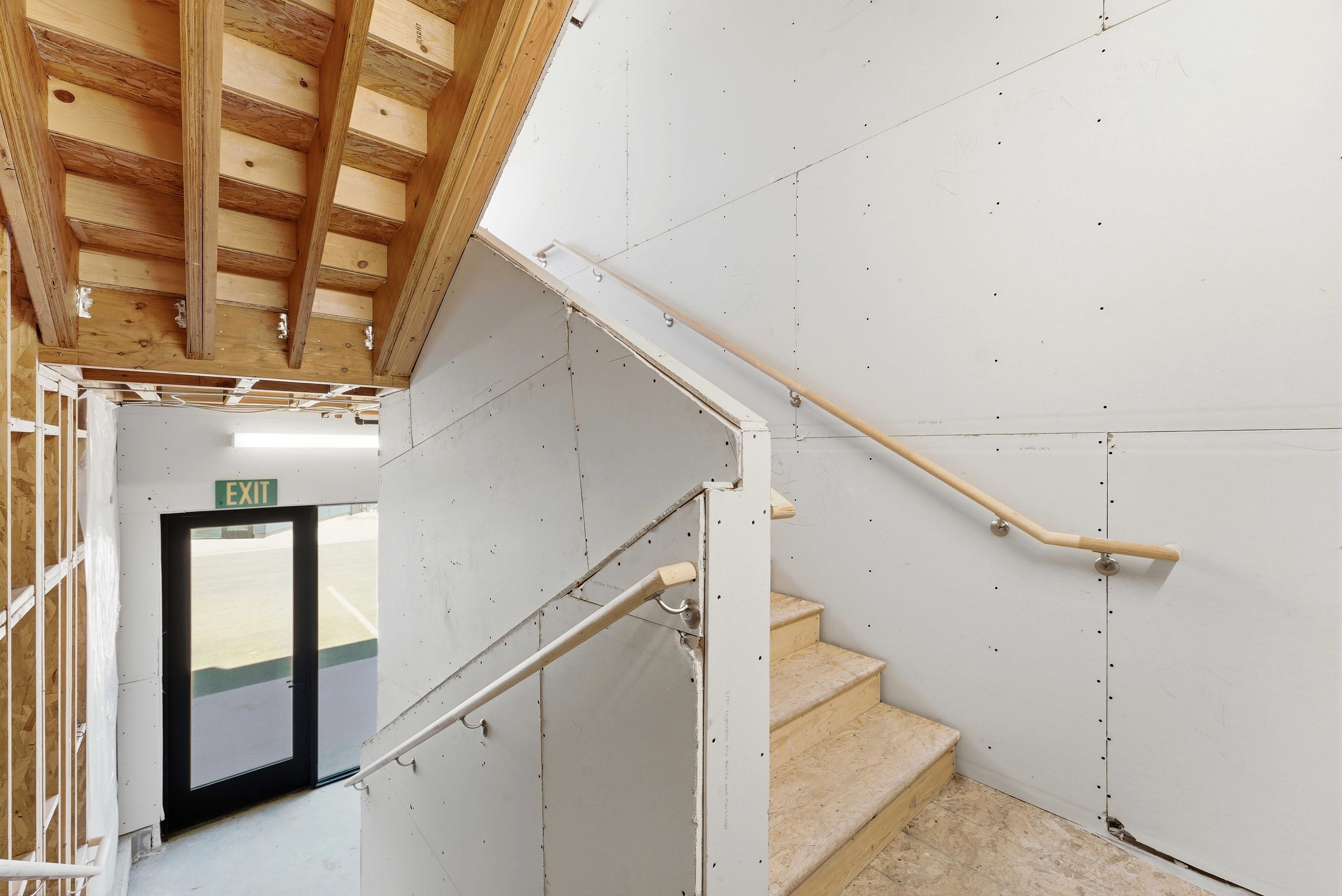 Staircase with unfinished wood steps and natural wood handrails