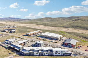 Aerial perspective showcasing a residential and commercial development situated amidst undulating natural terrain
