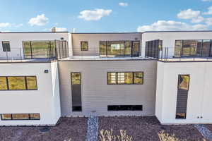 Modern architectural exterior featuring multiple balconies with metal railings, large windows, and contrasting white and gray siding