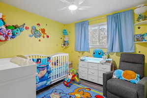 Bedroom featuring wood-finish flooring, a ceiling fan, and two windows with blinds