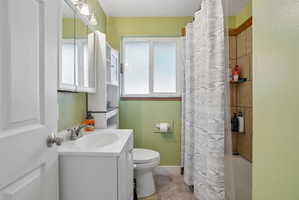 Bathroom featuring a white vanity with an integrated sink, three-door mirrored medicine cabinet, and a tiled shower surround