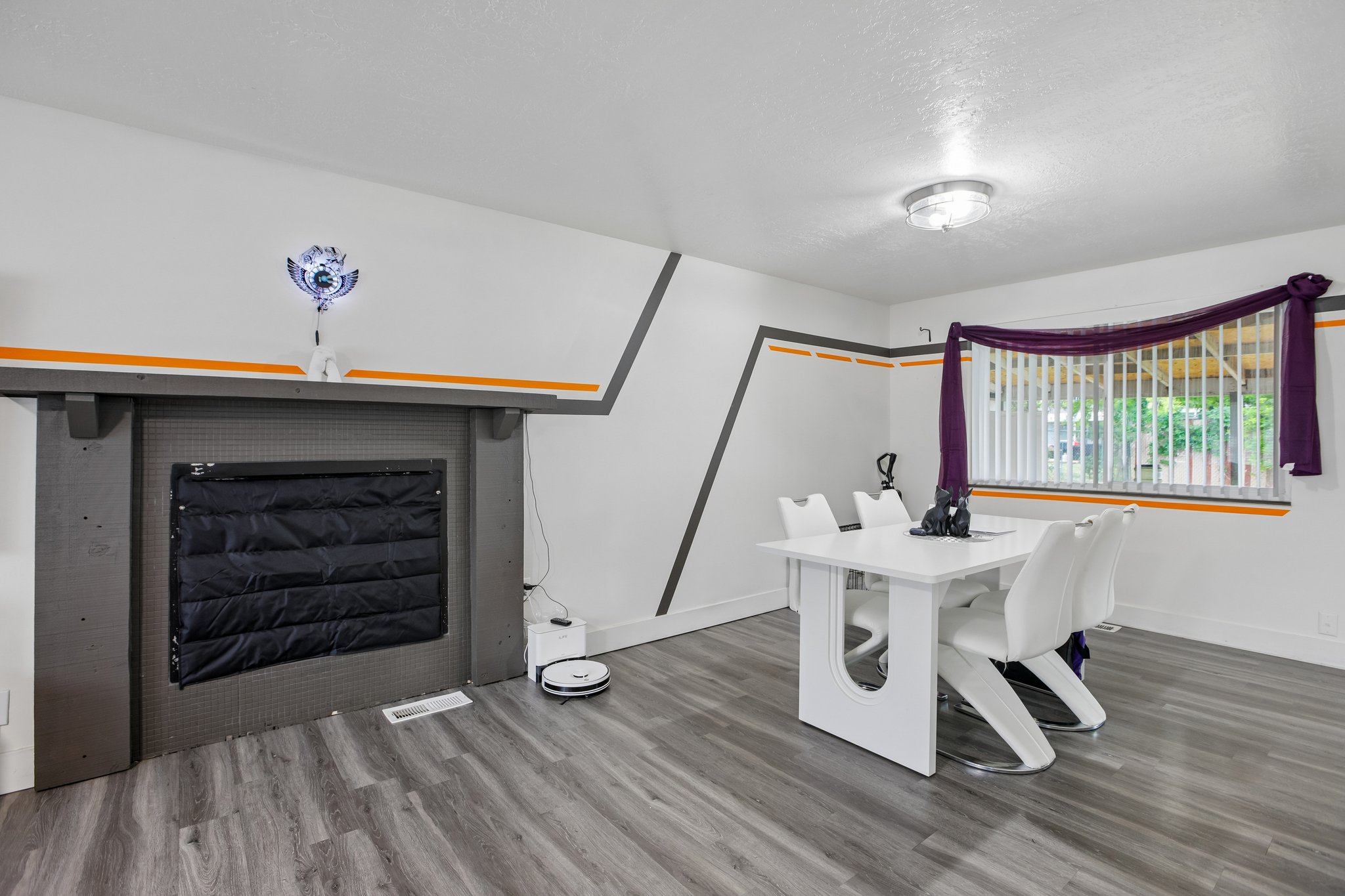 Spacious room featuring wood-finish flooring and a decorative fireplace with a substantial mantel
