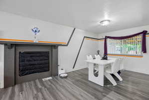 Spacious room featuring wood-finish flooring and a decorative fireplace with a substantial mantel