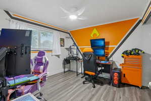 Interior room featuring wood-finish flooring, a ceiling fan with integrated lighting, and a white-trimmed window with blinds