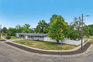 Corner lot residence featuring a light gray exterior with dark shutters