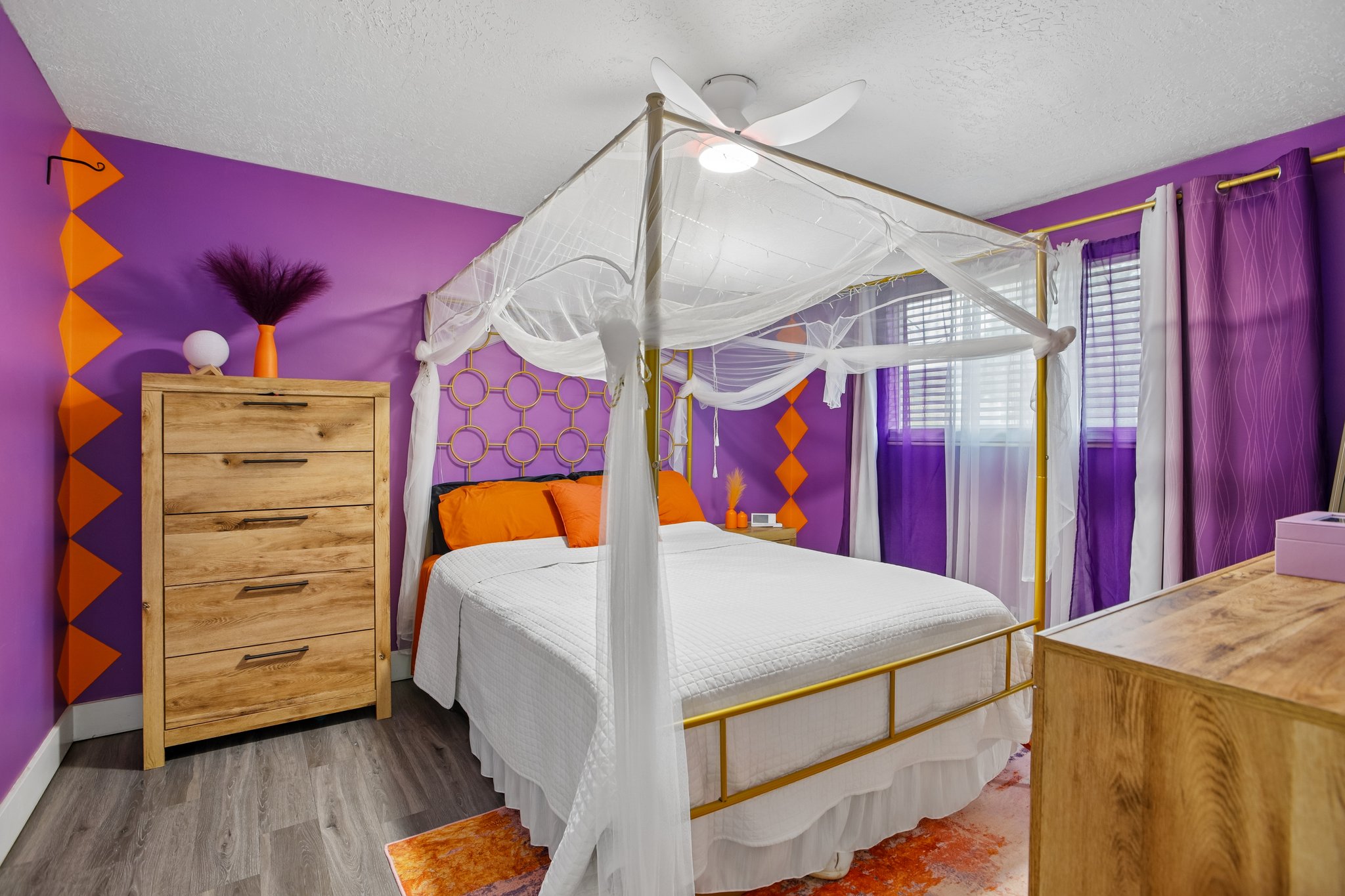 Bedroom featuring wood-finish flooring, a ceiling fan, and two windows with blinds and curtains