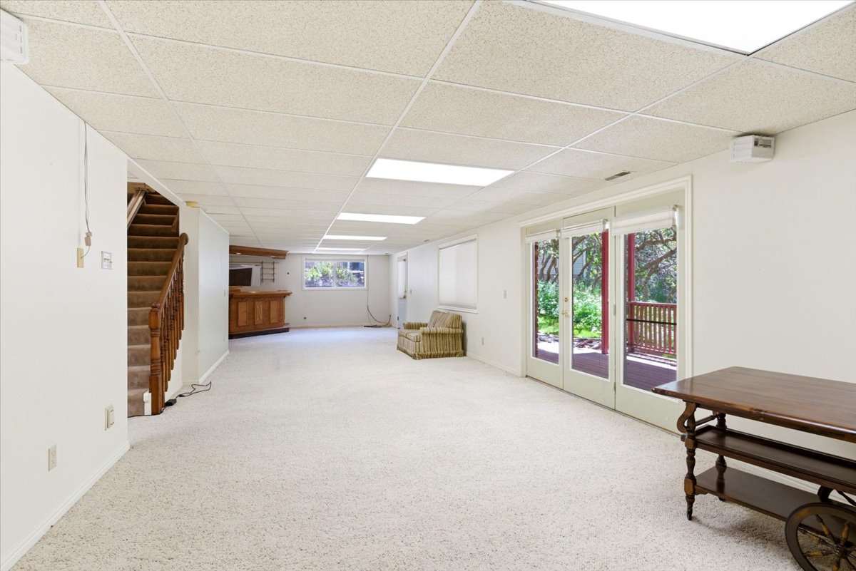 Spacious interior room featuring light-colored carpeting and a drop ceiling with recessed lighting