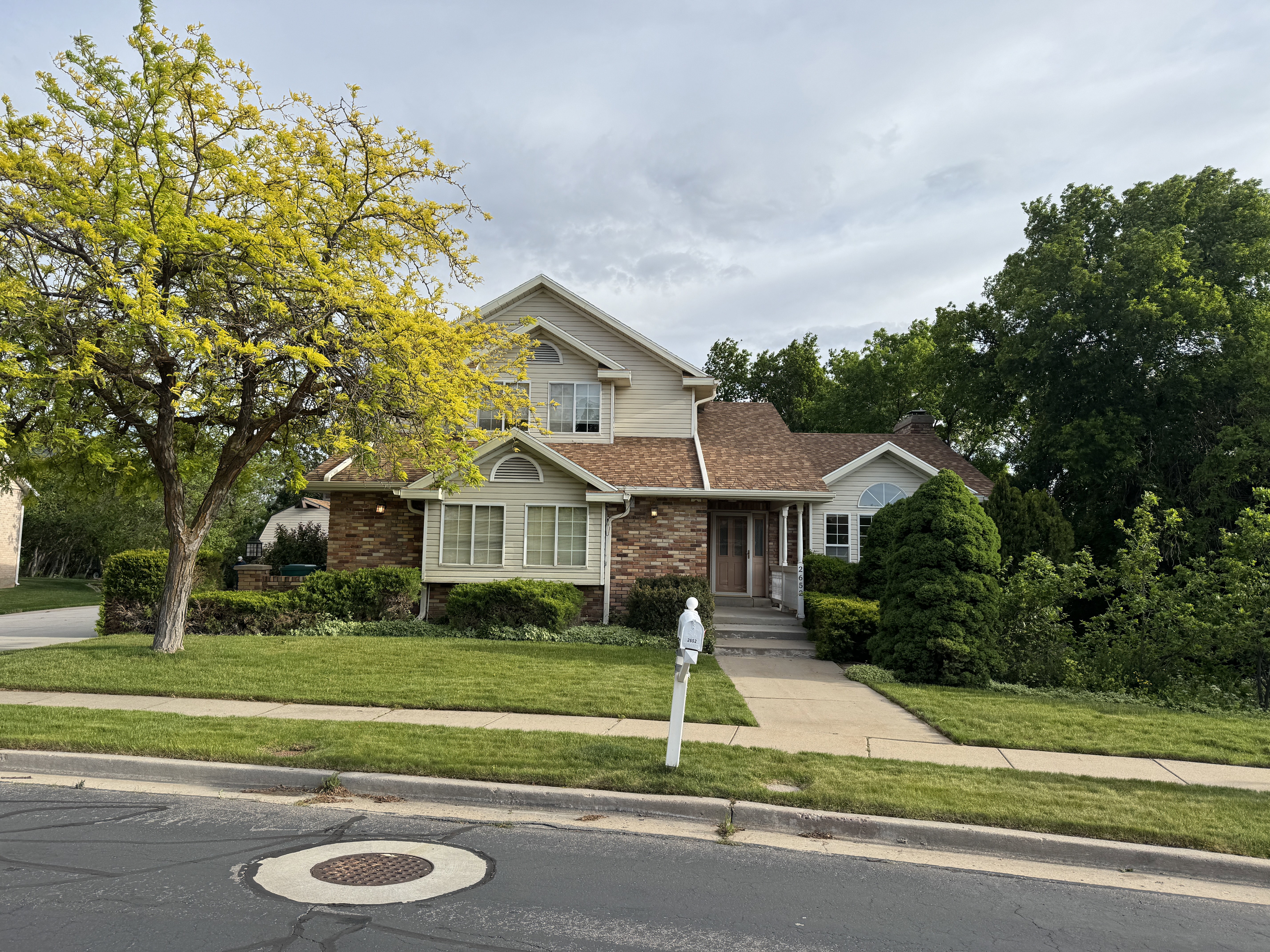 Two-story residence featuring brick and siding exterior, a gabled roofline, and mature landscaping
