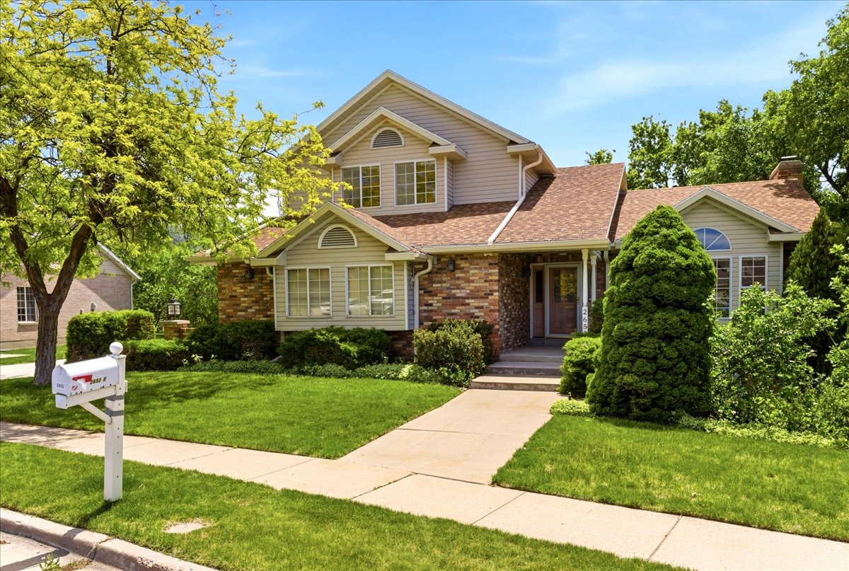 Traditional architectural style home featuring brick and siding accents, a prominent entryway, multiple gables, and a mature tree providing shade