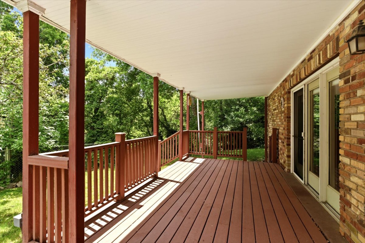 Expansive covered deck featuring wood-finish flooring and a full railing system