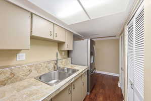 Kitchen area featuring dual stainless steel sinks, tiled countertops with matching backsplash, and light-toned cabinetry