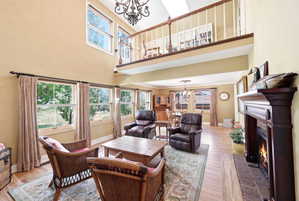 Two-story living area featuring wood-finish flooring, a grand fireplace with a dark wood mantel, and a second-story overlook with an open railing