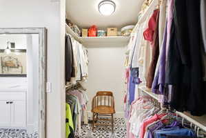 Walk-in closet featuring patterned floor tile, recessed ceiling light, and extensive built-in shelving with hanging rods