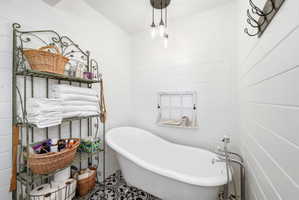 Freestanding slipper bathtub with floor-mounted faucet, set against shiplap-style walls