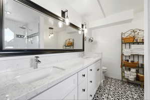Dual vanity featuring a white countertop with integrated sinks, black hardware, and an expansive framed mirror