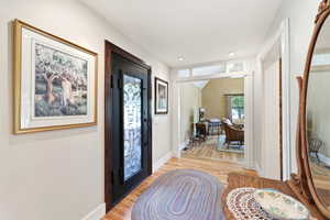 Entryway featuring a dark-framed glass door with decorative ironwork, hardwood flooring, recessed ceiling lighting, and crisp white trim