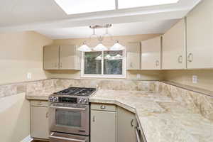 Kitchen featuring an integrated stainless steel range and oven, tile countertops, and a tile backsplash