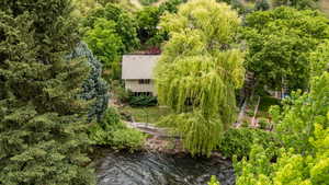 Riverside property featuring a two-story residence with a gabled roof and surrounding mature trees