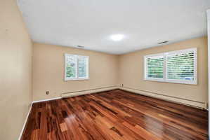 Rich wood-finish flooring provides a striking contrast with the neutral wall tones