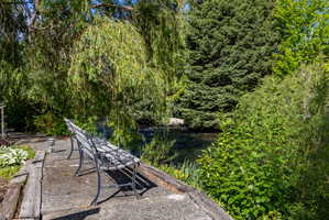 Waterside patio featuring a concrete surface, wooden borders, and a decorative metal bench