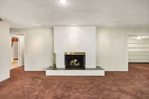 Living area featuring a painted brick fireplace with a brass surround and a tiled hearth