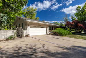 Single-story residence featuring light-colored brick exterior, attached two-car garage, and a concrete driveway