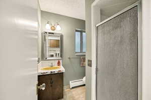 Bathroom featuring a decorative vanity mirror, a vanity light fixture with two sconces, a wood-finish vanity cabinet, and an enclosed shower with textured glass