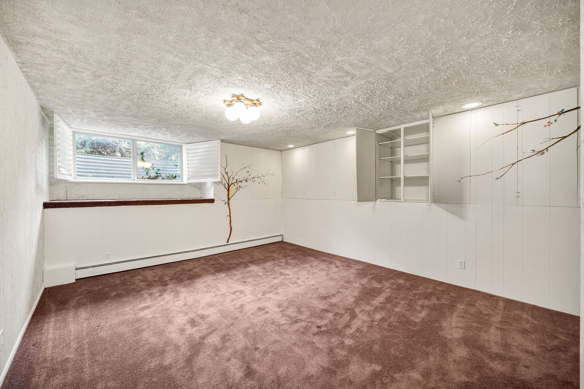 Spacious room featuring carpeting, a multi-pane window with plantation shutters, built-in shelving, and recessed lighting, with additional flush-mount lighting