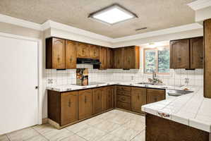 Kitchen featuring extensive wood cabinetry, tile countertops, and a tile backsplash