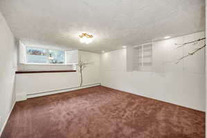 Spacious room featuring brown carpeting, a window with white shutters, a decorative wall decal, built-in cabinetry, and recessed lighting