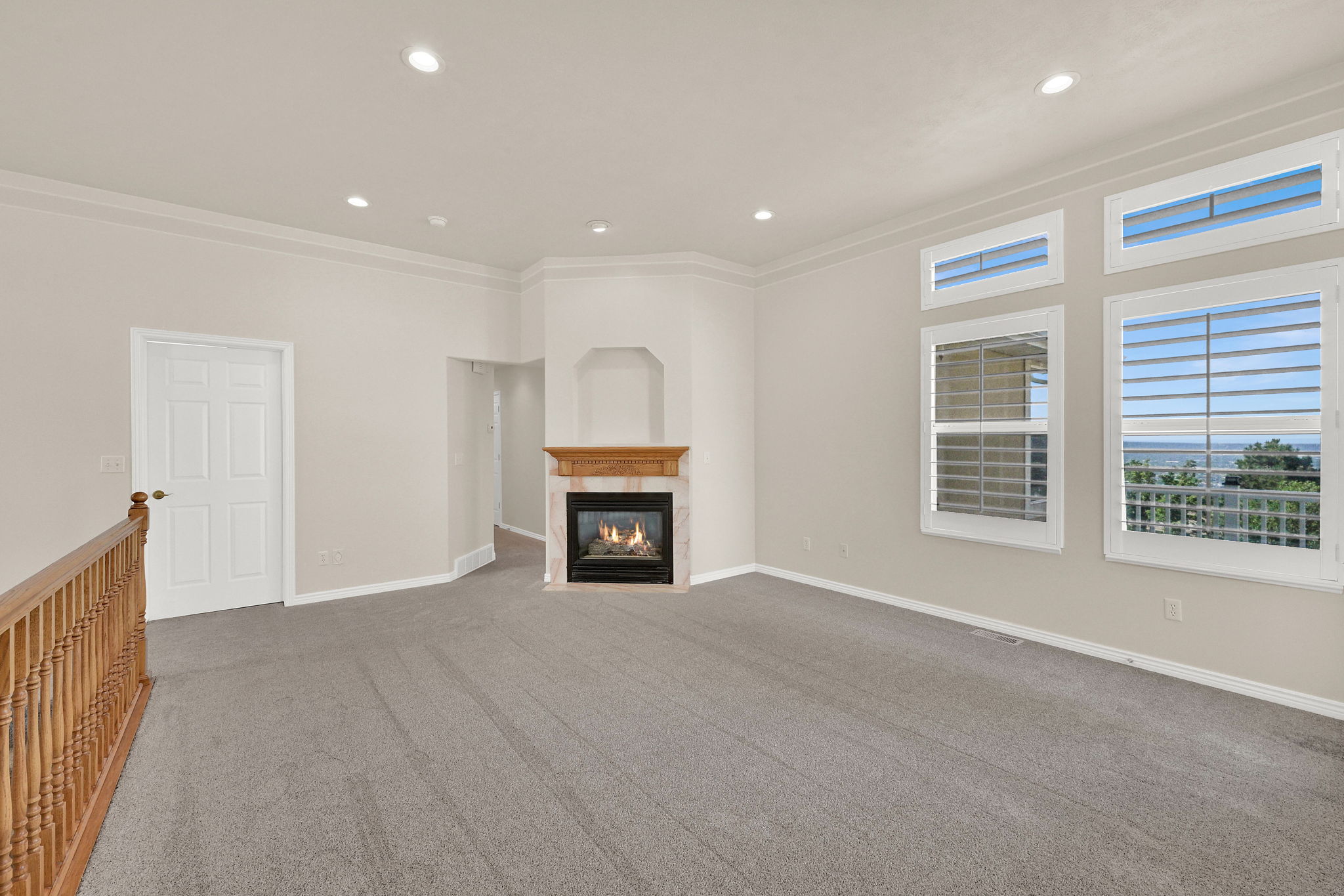 Living area featuring a gas fireplace with a wood mantle, recessed lighting, and grey carpet