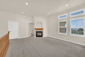Living area featuring a gas fireplace with a wood mantle, recessed lighting, and grey carpet