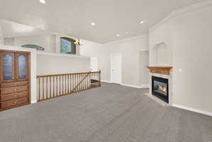 Spacious room with light gray carpeting and a gas fireplace featuring a wood mantel and stone surround