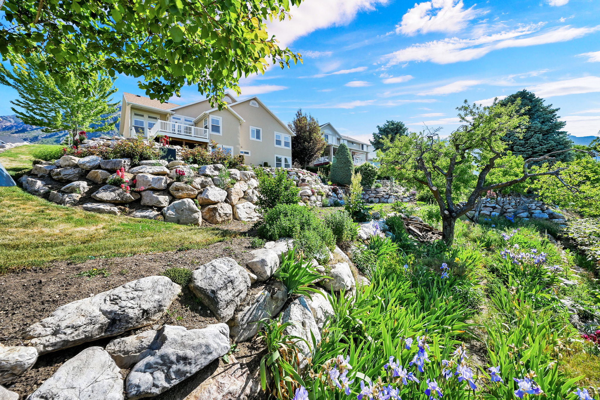 Terraced landscaping with natural rock retaining walls, mature trees, and established plantings