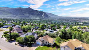 Expansive neighborhood featuring varied residential architecture, mature tree canopies, and distant mountain ranges