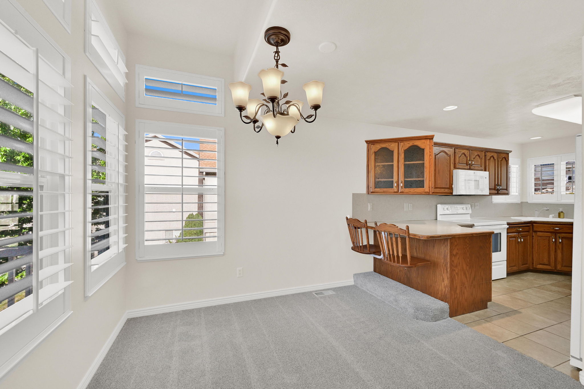 Dining area with white shuttered windows, a chandelier, and plush grey carpeting
