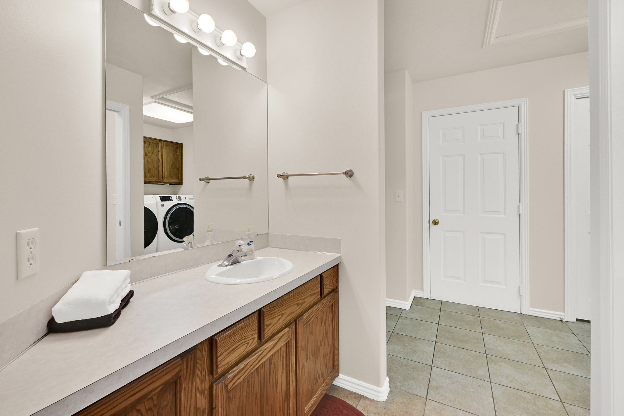 Bathroom vanity featuring wood cabinetry, a light-colored countertop, and an integrated sink with a chrome faucet
